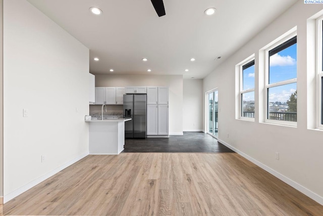 kitchen featuring stainless steel refrigerator with ice dispenser, sink, white cabinetry, wood-type flooring, and ceiling fan