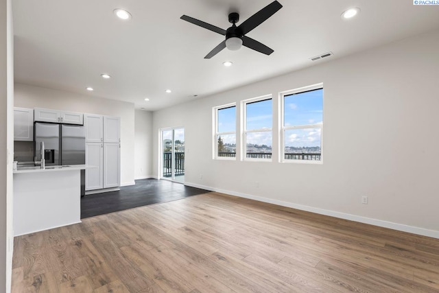 unfurnished living room with wood-type flooring and ceiling fan