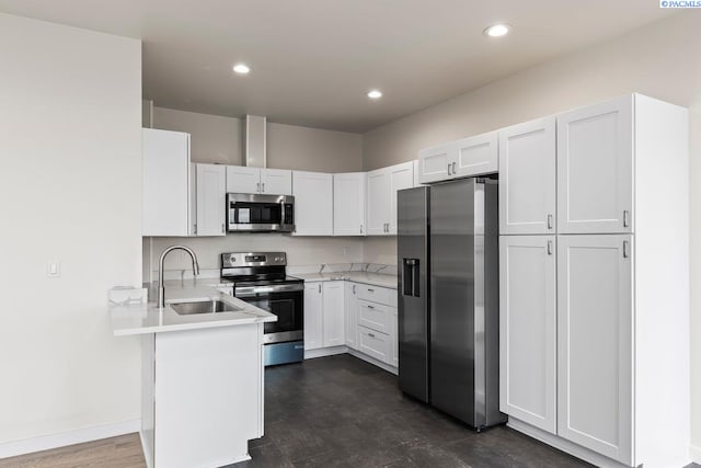 kitchen featuring appliances with stainless steel finishes, sink, white cabinets, and kitchen peninsula