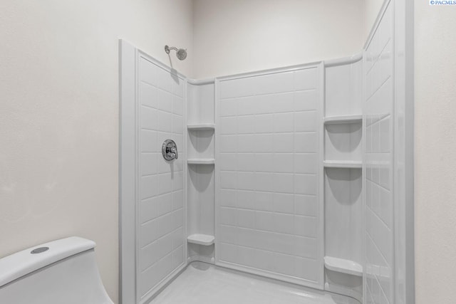 bathroom featuring toilet and a tile shower