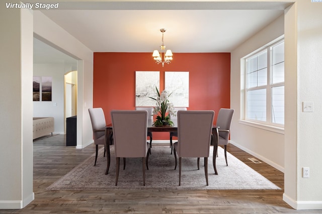 dining space featuring arched walkways, a notable chandelier, baseboards, and wood finished floors