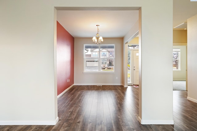 unfurnished dining area featuring a chandelier, a wealth of natural light, baseboards, and dark wood-style floors