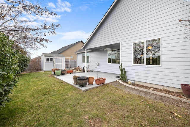 rear view of house with an outbuilding, a yard, a patio, a storage unit, and a ceiling fan