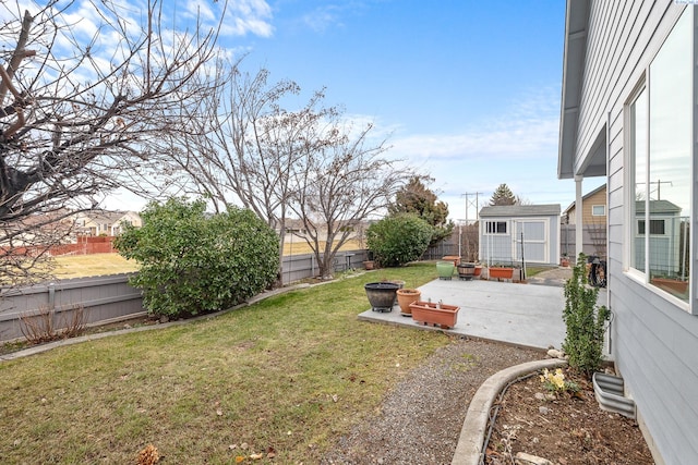 view of yard with a storage shed, an outdoor fire pit, a fenced backyard, an outdoor structure, and a patio area