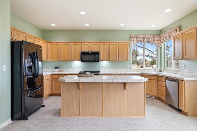 kitchen featuring recessed lighting, a kitchen island, a sink, tile counters, and black appliances