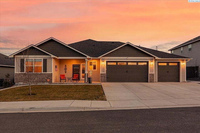 craftsman house with concrete driveway, stone siding, a lawn, and an attached garage