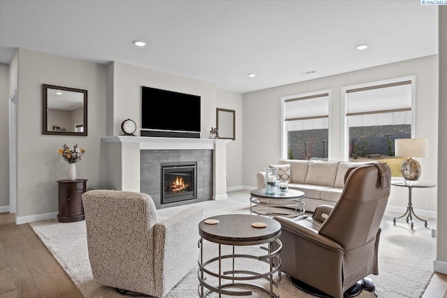 living area featuring wood finished floors, recessed lighting, a tile fireplace, and baseboards