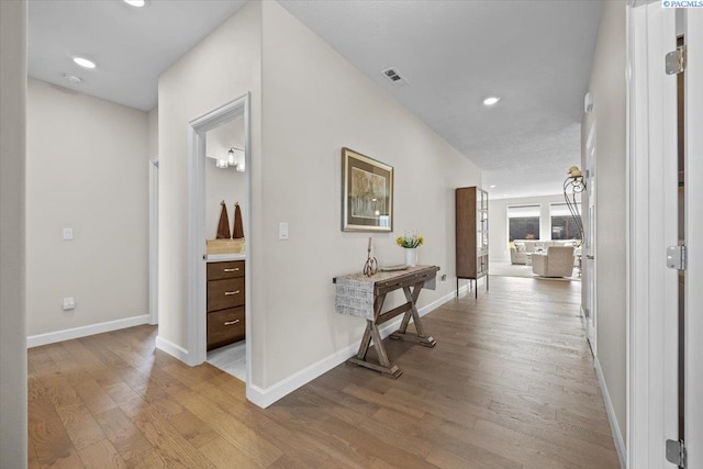 corridor with light wood-style floors, recessed lighting, visible vents, and baseboards