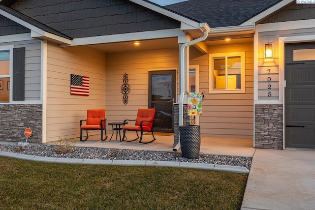 property entrance with a garage, stone siding, roof with shingles, and a porch