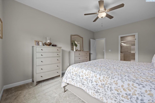 bedroom featuring light carpet, ensuite bathroom, a ceiling fan, and baseboards