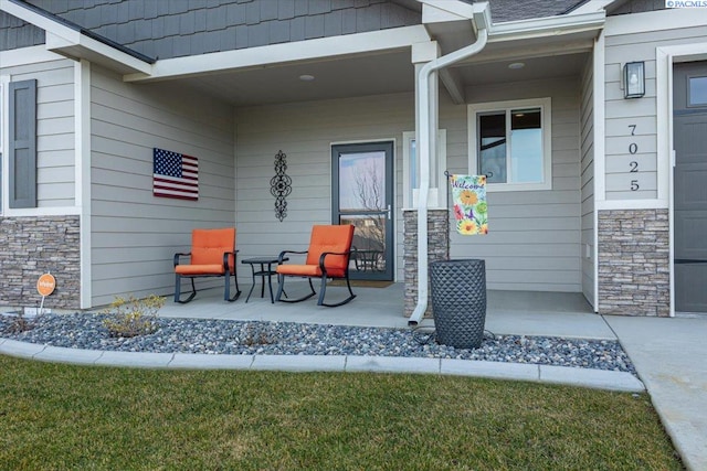 view of exterior entry with stone siding and covered porch