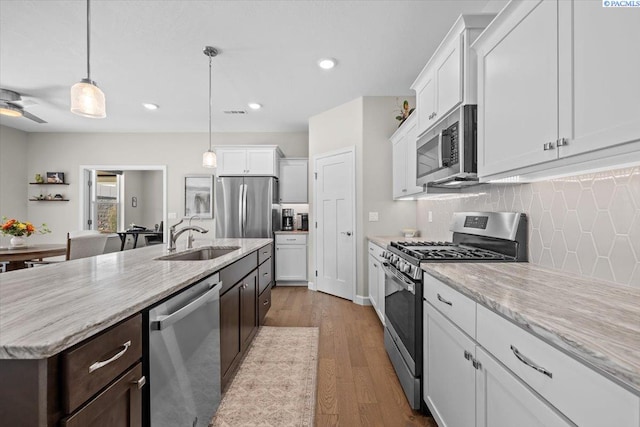 kitchen featuring appliances with stainless steel finishes, white cabinets, a sink, and wood finished floors