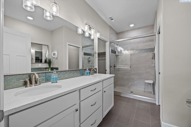 full bath featuring double vanity, a sink, visible vents, and a shower stall