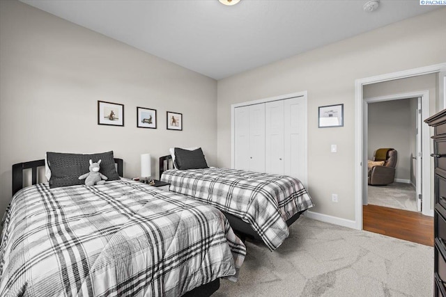 carpeted bedroom featuring a closet and baseboards