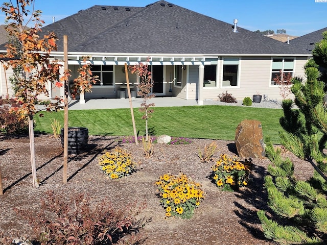 back of property with a patio, a yard, and roof with shingles