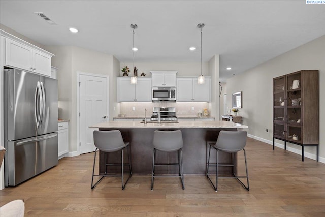 kitchen with stainless steel appliances, visible vents, backsplash, white cabinets, and light wood-type flooring