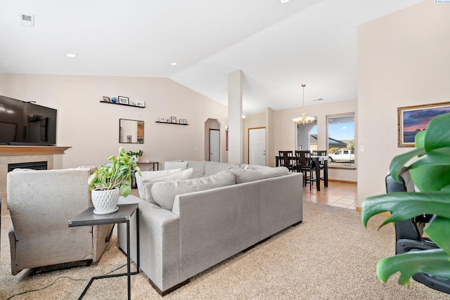 tiled living room featuring a tile fireplace, vaulted ceiling, and an inviting chandelier