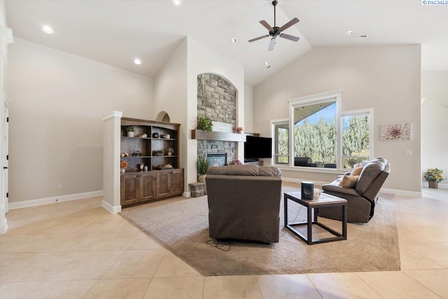 living room with ceiling fan, a stone fireplace, light tile patterned floors, and high vaulted ceiling