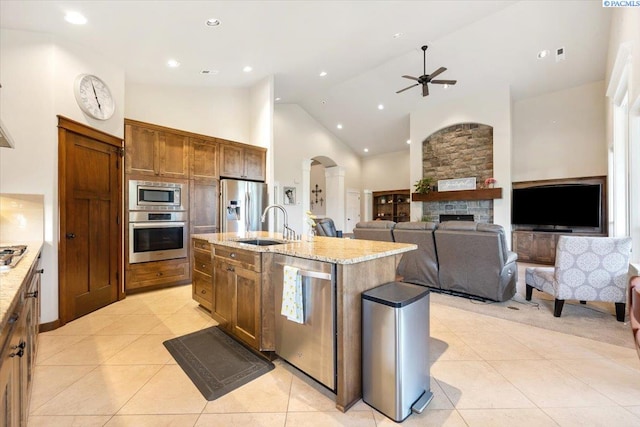 kitchen with sink, appliances with stainless steel finishes, high vaulted ceiling, an island with sink, and light tile patterned flooring