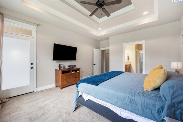 carpeted bedroom featuring crown molding, a tray ceiling, ceiling fan, and ensuite bathroom