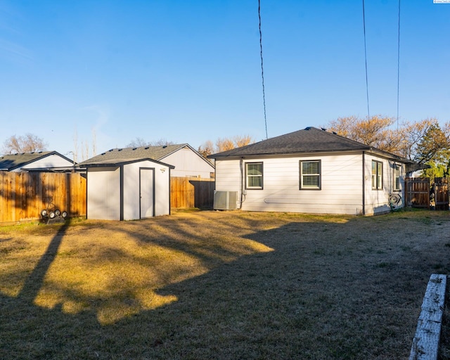 back of property featuring an outbuilding, a fenced backyard, a yard, and a shed