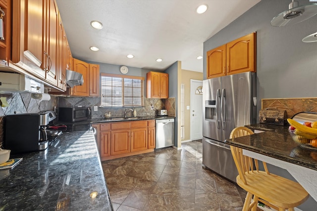 kitchen with tasteful backsplash, ventilation hood, sink, dark stone countertops, and stainless steel appliances