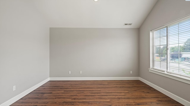 unfurnished room with healthy amount of natural light, vaulted ceiling, dark wood-type flooring, and baseboards