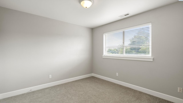 empty room featuring baseboards and light carpet