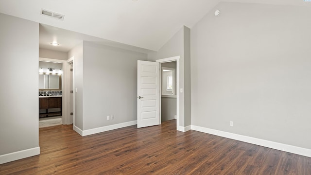 unfurnished bedroom featuring baseboards, dark wood finished floors, and lofted ceiling