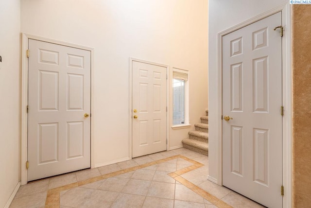 entrance foyer with light tile patterned floors, stairs, and baseboards