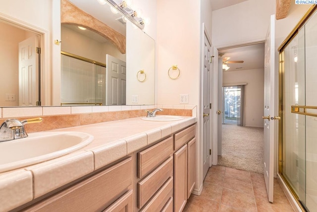 full bath with double vanity, a stall shower, tile patterned flooring, and a sink