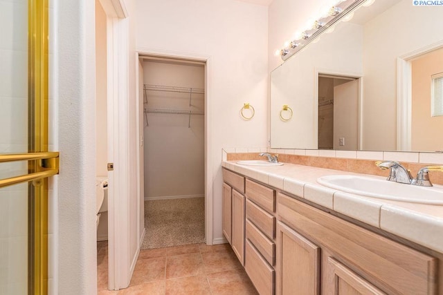 full bathroom with tile patterned flooring, a sink, a spacious closet, and double vanity