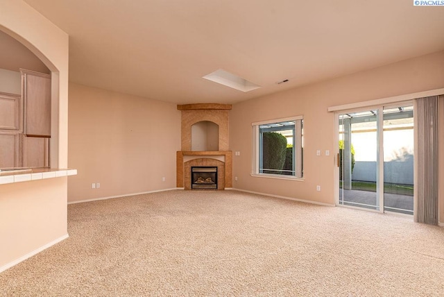 unfurnished living room featuring light carpet, visible vents, baseboards, and a tiled fireplace