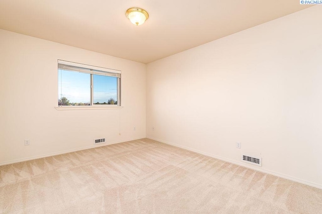 spare room with light colored carpet, visible vents, and baseboards