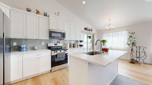 1609 Diamond Ave, Grandview, WA 98930 - kitchen with stainless steel appliances, lofted ceiling, light wood-style flooring, decorative backsplash, and white cabinetry
