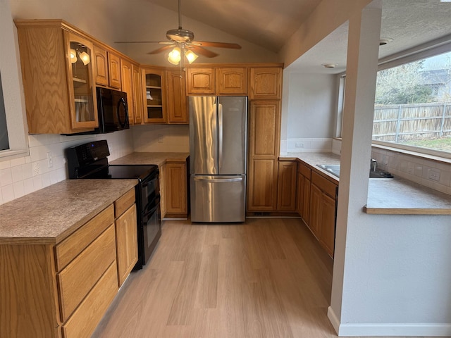 kitchen with sink, tasteful backsplash, vaulted ceiling, light hardwood / wood-style floors, and black appliances