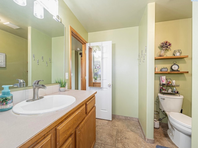 612 S Young St, Kennewick, WA 99336 - bathroom featuring toilet, vanity, baseboards, and stone finish flooring