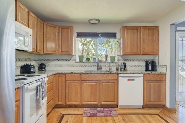 kitchen with light stone countertops, white appliances, a wealth of natural light, and a sink