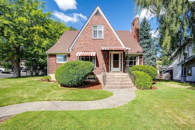 912 S Lake St, Colfax, WA 99111 - tudor home featuring brick siding, a chimney, a front lawn, and a shingled roof