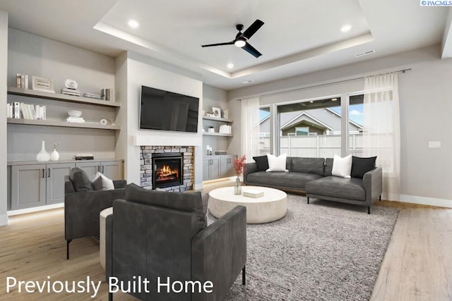 12101 Vincenzo Dr, Pasco, WA 99301 - living room featuring a ceiling fan, a raised ceiling, light wood-style floors, and a stone fireplace