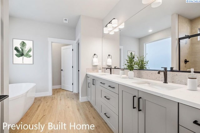 12101 Vincenzo Dr, Pasco, WA 99301 - full bathroom with a sink, a shower stall, double vanity, a freestanding bath, and wood finished floors