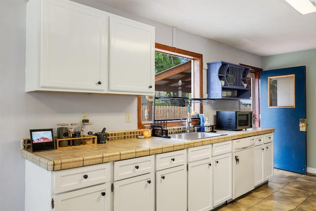 kitchen featuring white cabinets, tile counters, sink, and white dishwasher