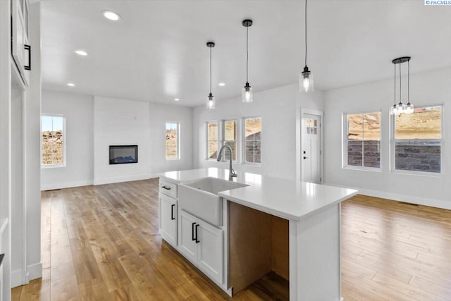 903 Ellen Ln, Zillah, WA 98953 - kitchen featuring sink, hanging light fixtures, a large fireplace, white cabinets, and a center island with sink
