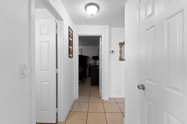 corridor featuring a textured ceiling and light tile patterned floors