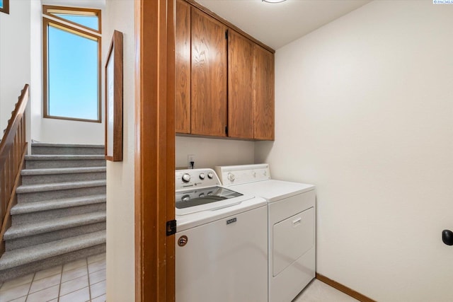 clothes washing area with cabinet space, light tile patterned floors, and independent washer and dryer