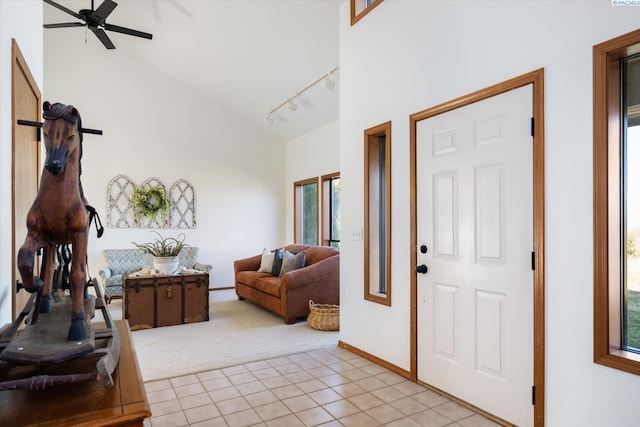 entryway featuring light carpet, light tile patterned floors, baseboards, high vaulted ceiling, and track lighting