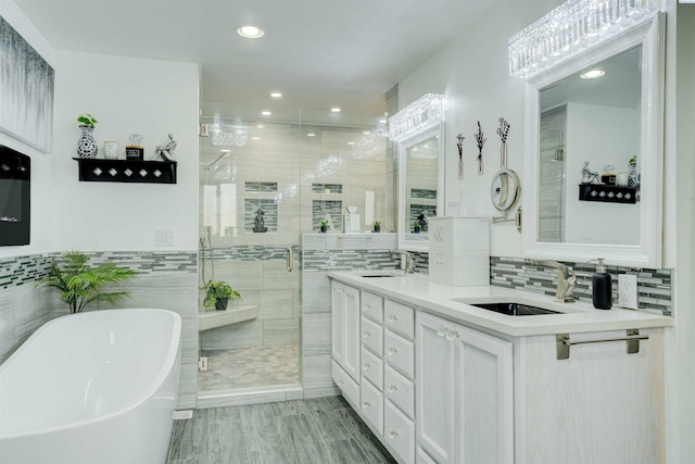 full bath with double vanity, a freestanding tub, a stall shower, and a sink