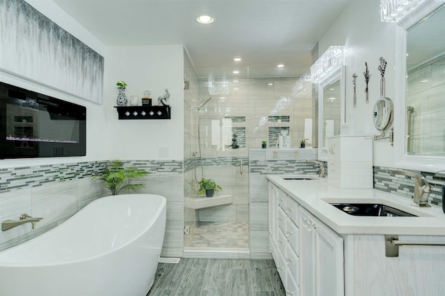 bathroom featuring double vanity, a freestanding tub, a stall shower, and a sink