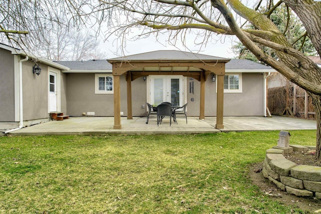 rear view of property featuring stucco siding, french doors, a lawn, and a patio