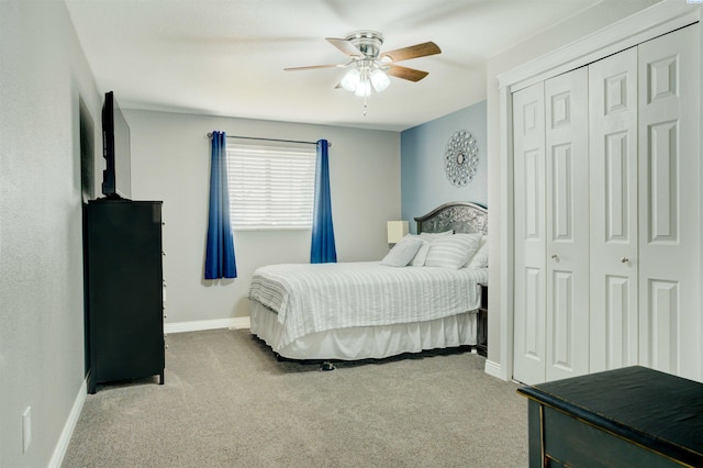 bedroom featuring light carpet, ceiling fan, baseboards, and a closet